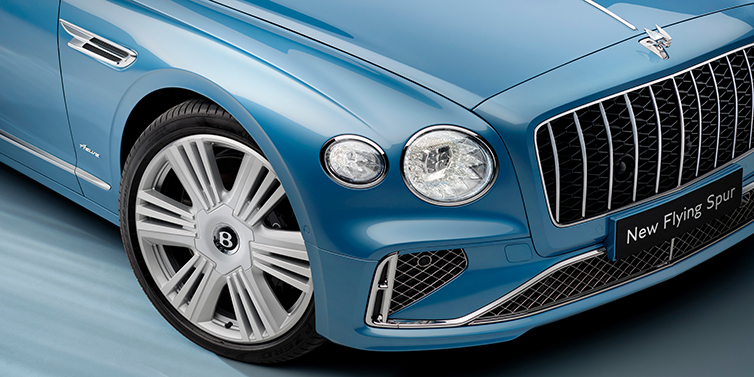 Bentley Kuwait Bentley Flying Spur Speed sedan exterior close up in Tourmaline Green paint with chrome B wing vent, chrome Speed badge and 22 inch ten swept spoke wheel
